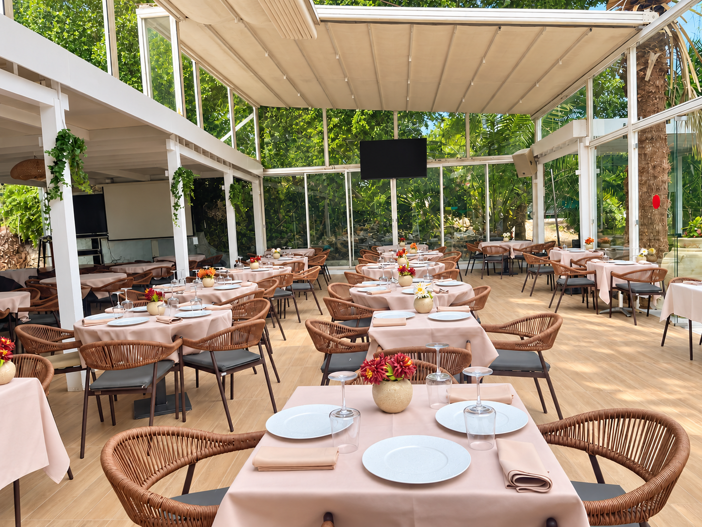 La véranda lumineuse du Pirate, ses tables beige rosé et ses fauteuils en rotin